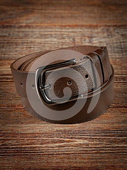 Brown leather belt on a wooden brown background