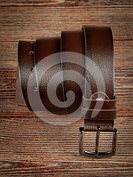 Brown leather belt on a wooden brown background