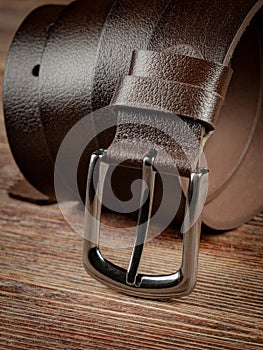 Brown leather belt on a wooden brown background