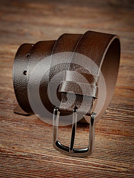 Brown leather belt on a wooden brown background