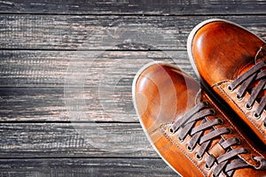 Brown leather boots on wooden background top view with copy space