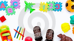 Brown leather children`s sandals with colorful  toys on white background.