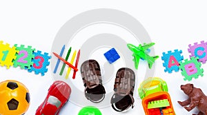 Brown leather children`s sandals with colorful  toys on white background.
