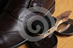 Brown leather classic Brogue shoes with polishing cream and brush on a table