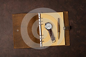 Brown leather diary and pen on brown background or table