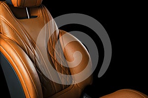 Brown leather interior of the luxury modern car. Perforated orange leather comfortable seats with stitching isolated on black back