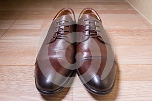 Brown leather men shoes on wooden ground
