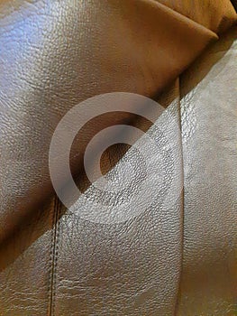 Brown leather surface with bend, fold. Background design, photography. Textile, fabric template, modern new