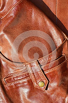 Brown leather texture. Useful as background for any design work. Macro photo of a button on outer clothing made of genuine leathe