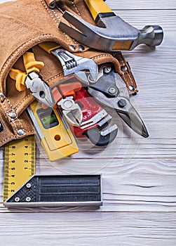 Brown leather toolbelt with construction tools on wood board dir photo