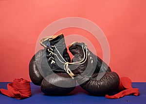 Brown leather vintage boxing gloves on a red background, sports equipment