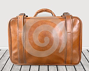 Brown leather vintage suitcase on wooden floor