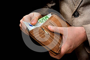 Brown leather wallet with euro money in male hands