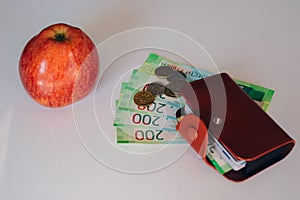 Brown leather wallet with plastic cards and Bank of Russia banknotes. Russian money for 200 rubles and coins. red apple
