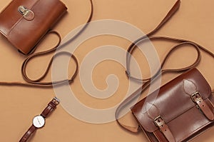 Brown leather women bag, stylish wristwatch on brown beige background top view flat lay copy space. Fashionable women`s