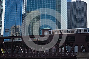 Brown line el train crosses the Wells St elevated train tracks with skyline in background