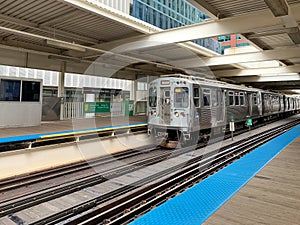 Brown line el train moving into Merchandise Mart station where the platform is empty at midday