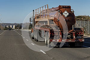 Brown liquid fuel tanker truck driving down road