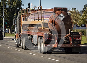 Brown liquid fuel tanker truck driving down road