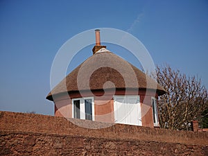 A brown local vintage historical cottage house with cone-shaped straw roofing and high stone walls by the seaside beach
