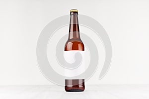 Brown longneck beer bottle 500ml with blank white label on white wooden board, mock up.