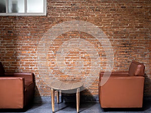 Brown luxury modern leather single sofa, side view with round wooden side table decorated on empty brick wall.