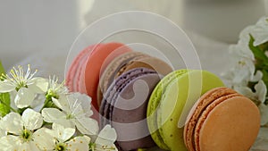 brown macaroons of red, brown purple, green and beige spins on white paper with apple blossoms