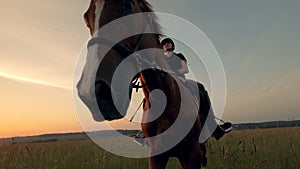 Brown mare is getting ridden by a female equestrian across an open field