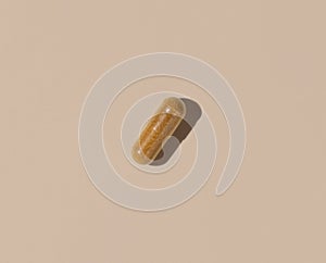 Brown Medical capsule on light beige top view, hard shadows. Taking dietary supplements