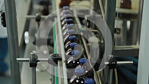 Brown medical vials on a conveyor belt at a drug manufacturing plant.