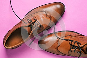 Brown men`s shoes close-up. Classic shoes with untied laces on a pink background. Shoes for weddings, everyday walking