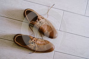 Brown men`s shoes with untied laces on a white laminate.