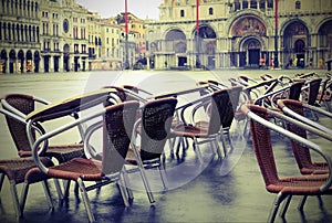 Brown and metal chairs submerged on Venice Square with old toned