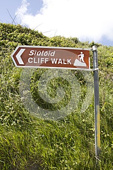 Brown metal direction sign for a cliff walk