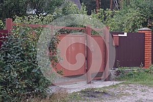 Brown metal gate and a closed door on a fence wall
