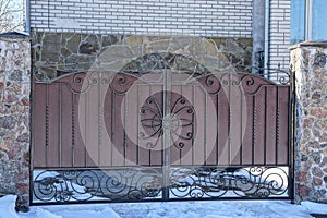 Brown metal gate on a fence in the street in the snow