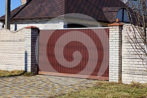 Brown metal gate and gray brick fence on a city street