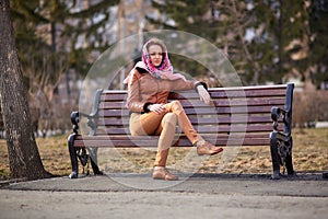 brown moccasins on the feet of a beautiful young woman who sits on a bench in the Park with a handkerchief on her head