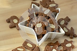 Brown moravian dark gingerbreads with sliced almonds, christmas cookies in white star shapped bowl