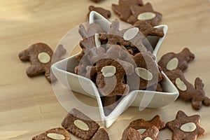Brown moravian dark gingerbreads with sliced almonds, christmas cookies in white star shapped bowl