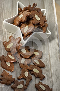 Brown moravian dark gingerbreads with sliced almonds, christmas cookies in white star shapped bowl