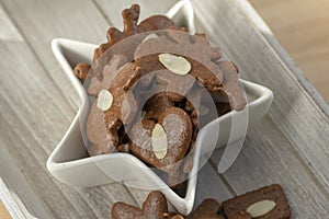 Brown moravian dark gingerbreads with sliced almonds, christmas cookies in white star shapped bowl