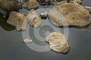 Brown natural rocks in water stream background.