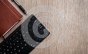 Brown notebook, black pen and computer keyboard on a wooden surface. Business concept. Business people items. Free space for text