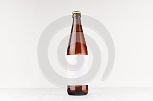 Brown NRW beer bottle 500ml with blank white label on white wooden board, mock up.