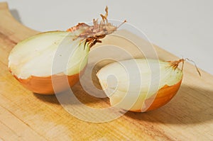 Brown onion or yellow onion or Bombay’s onion cut in half on a wooden cutting board