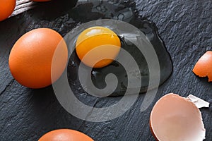 Brown organic cracked eggs with yolk on black background