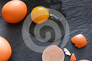 Brown organic cracked eggs with yolk on black background