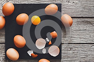 Brown organic cracked eggs with yolk on black wood background