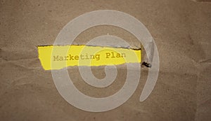 Brown packaging paper torn to reveal the words Marketing plan. Business concept photo